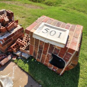 Damaged brick mailbox before rebuild with broken address panel section